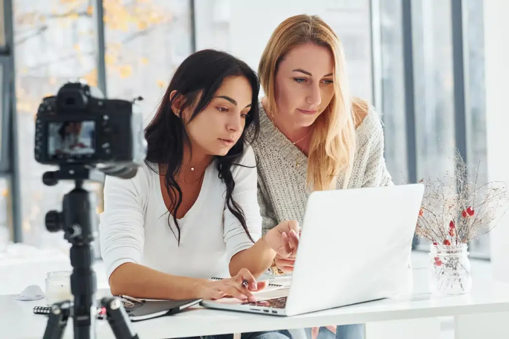 Women working on a laptop and filming a video, demonstrating how to personalize AI content to reflect their own voice
