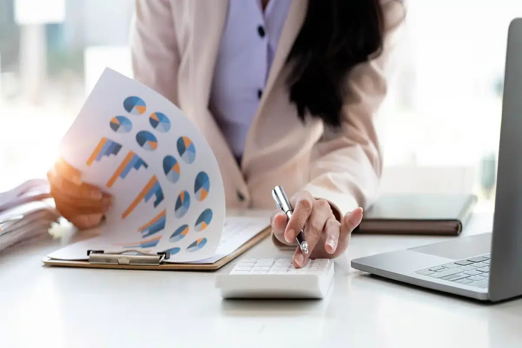 Woman reviewing charts with a calculator, illustrating strategies to maximize revenue through online courses