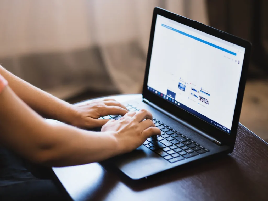 Hands typing on a laptop keyboard, showing creation of content from client questions and insights